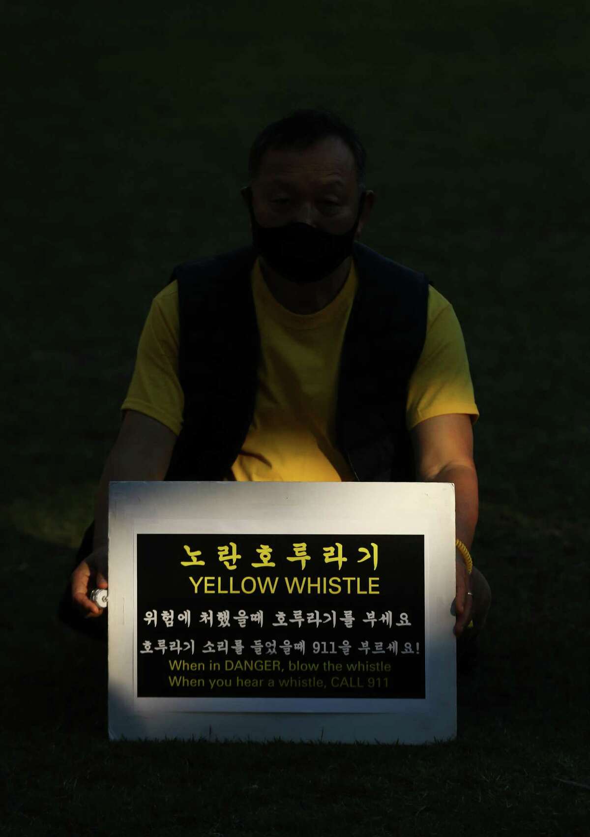 Joshua Na holds a sign which encourages people to blow a yellow whistle in dangerous situations, during a rally to commemorate the one-year anniversary of the Atlanta spa mass shootings where six Asian and Asian American women were killed, Discovery Green on Wednesday, March 16, 2022, in Houston. The event also highlighted the increase in violent crimes against memeber of the Asian and Asian American communities.