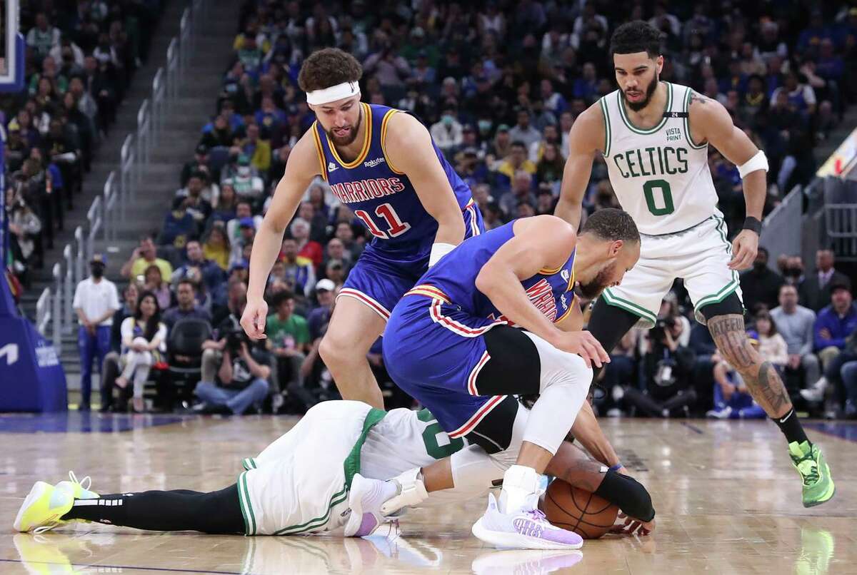 Golden State Warriors' Stephen Curry is injured as Boston Celtics' Marcus Smart dives for a loose ball in 2nd quarter during NBA game at Chase Center in San Francisco, Calif., on Wednesday, March 16, 2022.