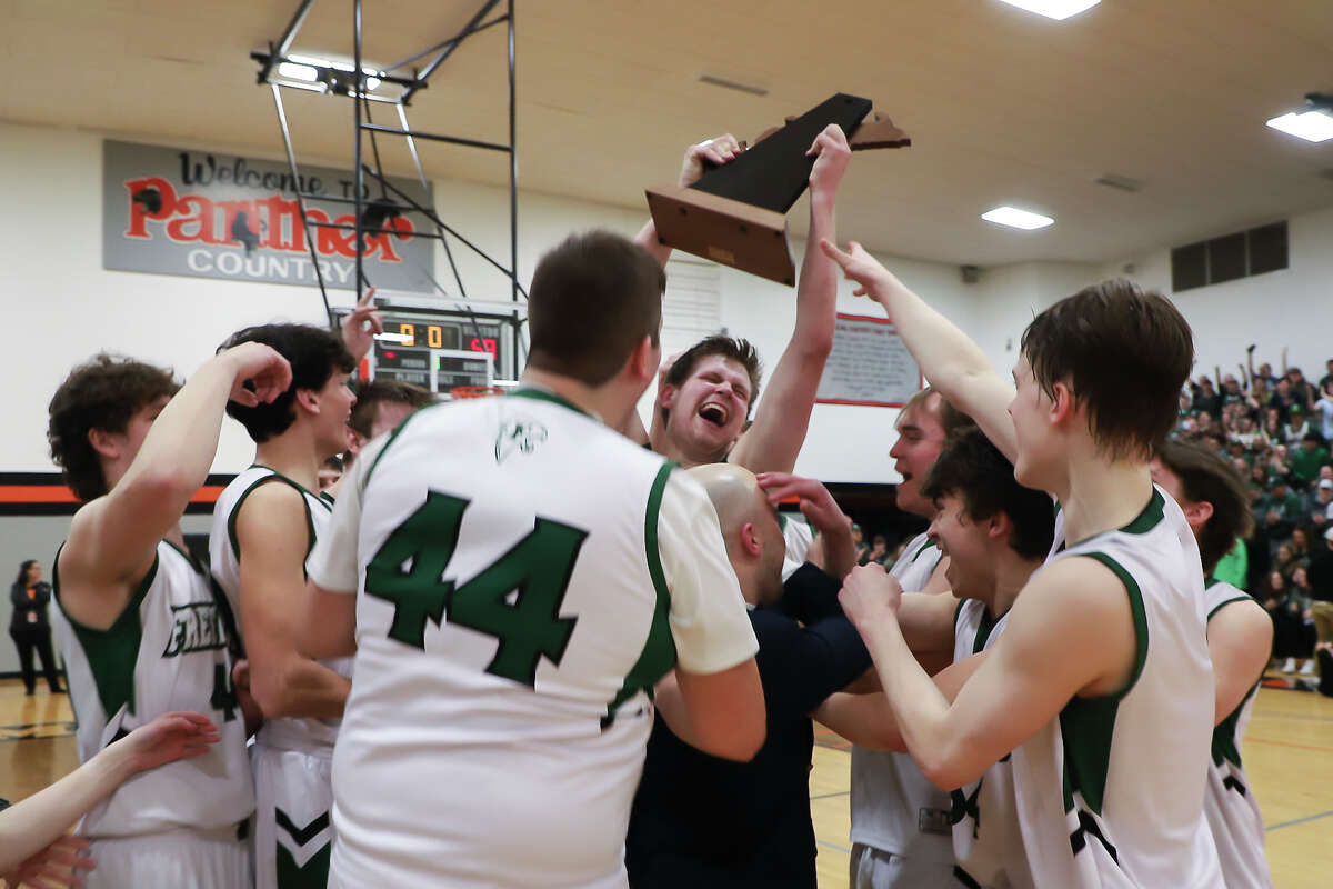 Freeland's Bryson Huckeby hoists the trophy into the air after the Falcons' regional final victory over Flint Hamady Tuesday, March 15, 2022 at Alma High School.
