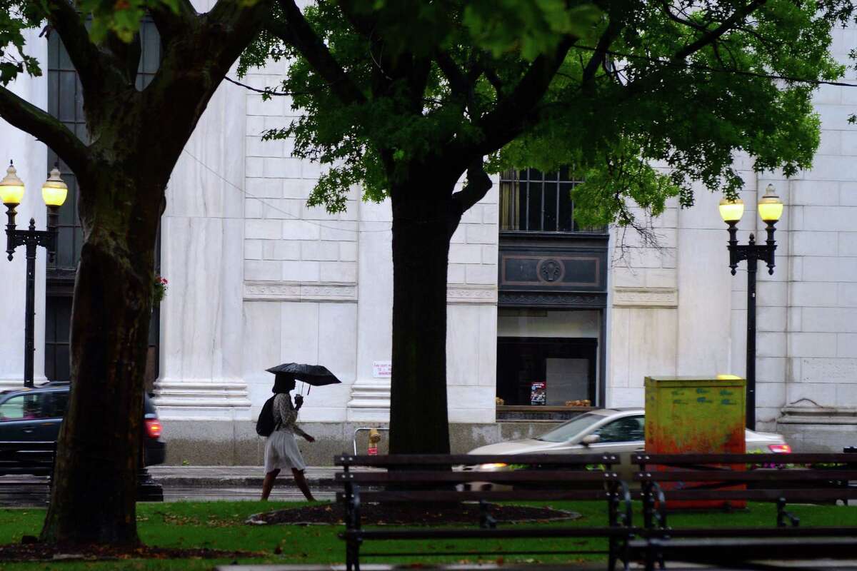 In this file photo, a pedestrian walks along State Street during a thunderstorm in downtown Bridgeport, Conn., on Tuesday, July 17, 2018.