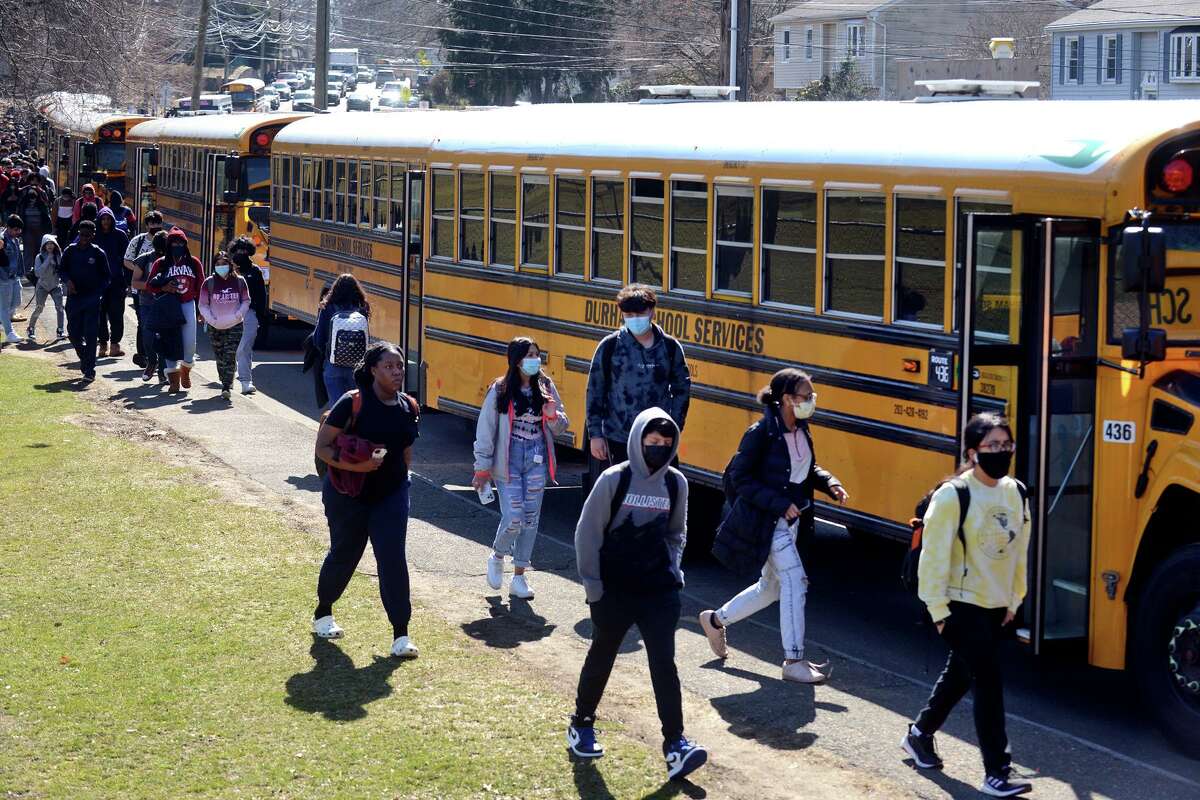 Students walk to their buses parked along Strawberry Hill Ave. at the end of the school day at Norwalk High School, in Norwalk, Conn. March 16, 2022.