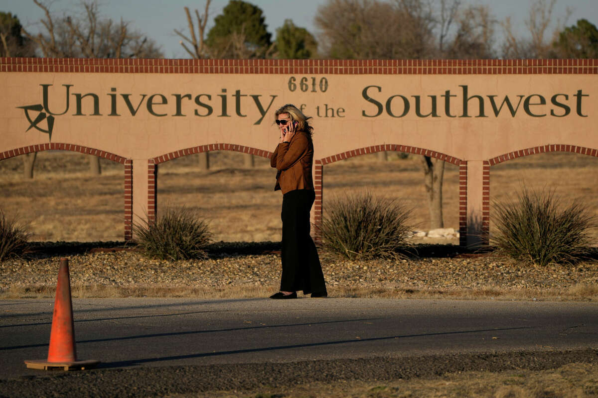A woman stands at the entrance to the University of the Southwest, Wednesday, March 16, 2022, in Hobbs, N.M. Students and a golf coach from the school were killed in a head-on collision in West Texas on Tuesday. (AP Photo/John Locher)