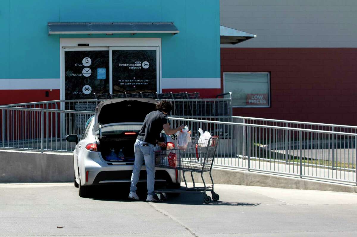 An H-E-B employee loads groceries into a customer’s car.