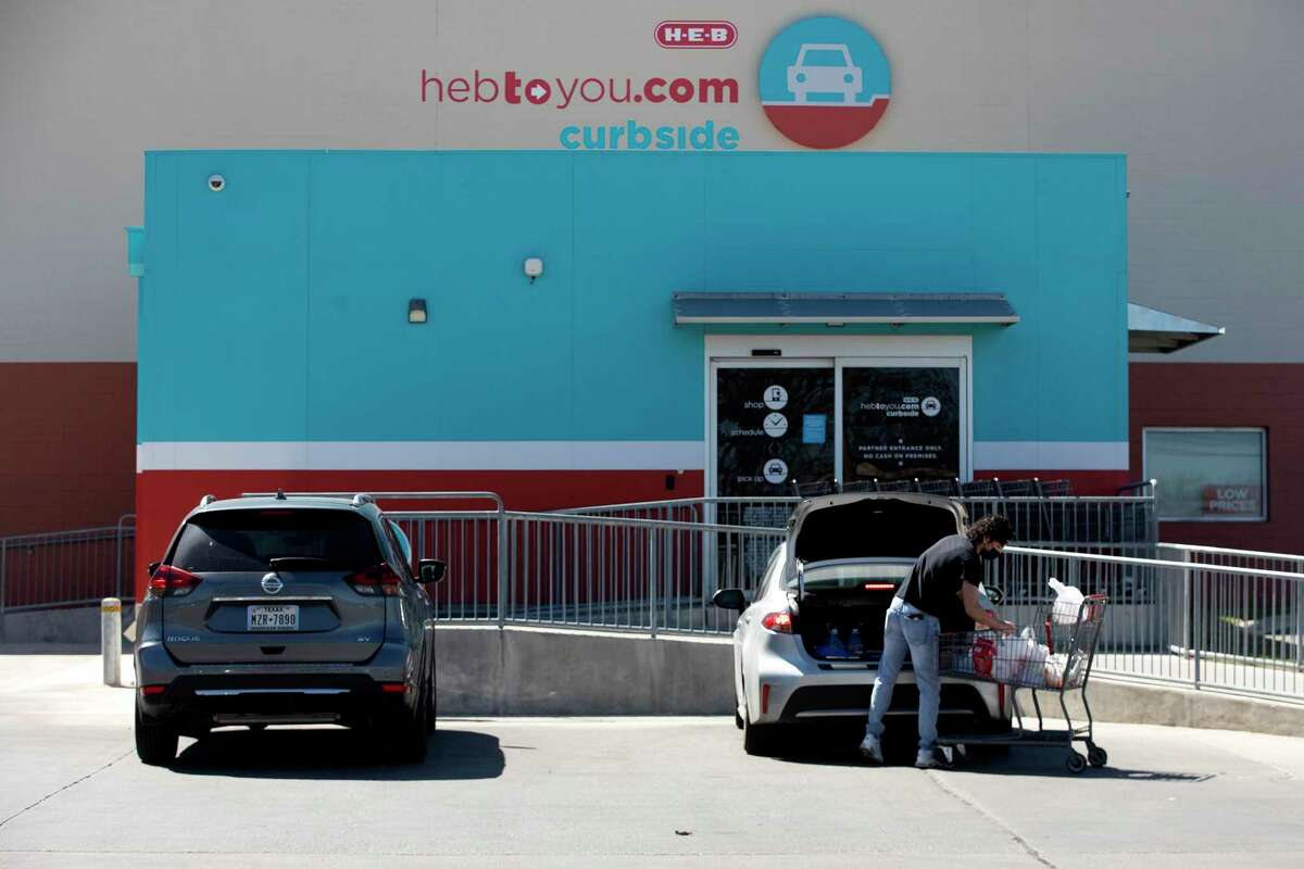 A H-E-B employee loads groceries into a customer’s car in the curbside pickup section of a San Antonio store.