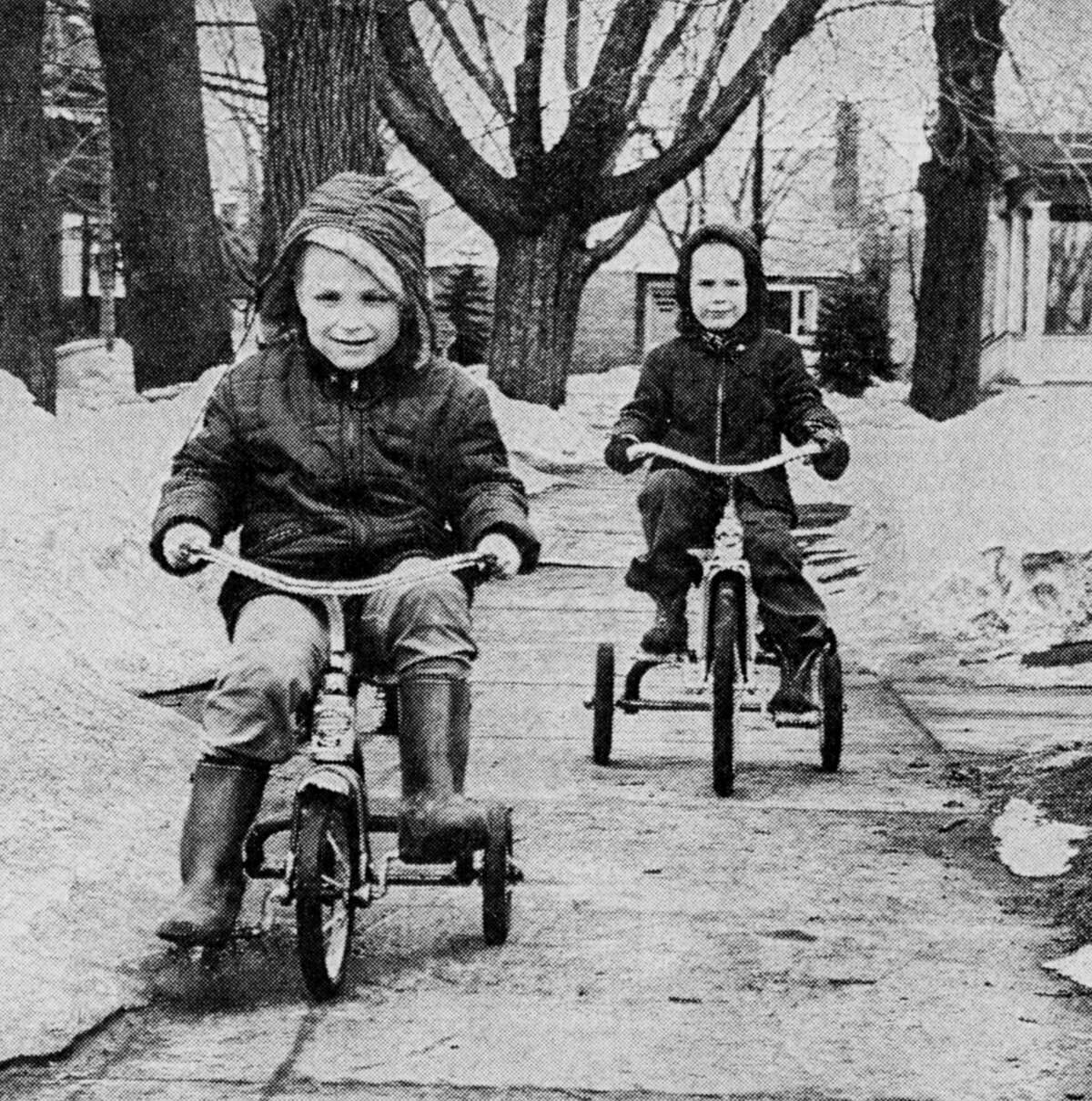 With the arrival of dry sidewalks in some areas, these youngsters bring in spring in typical fashion with a bike ride. Timothy Bedingham (front) and Peter Brastrom are shown riding bicycles between the still evident snow banks. The photo was published in the News Advocate on March 20, 1962.