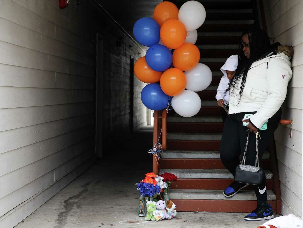 Sharde Williams and her son Carter, 3, look at the memorial that has been started for an 11-year-old boy who was fatally shot at an apartment complex on the 12200 block of Tidwell Road on Friday, Feb. 4, 2022, in Houston.