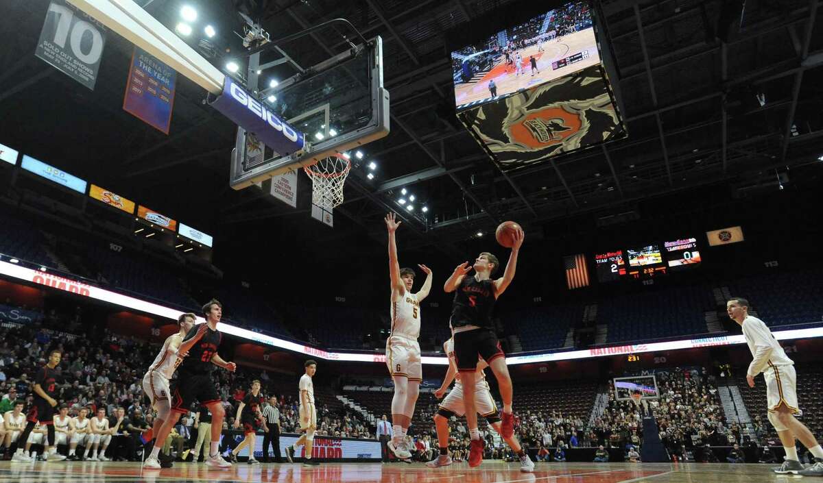 New Canaan's Alexander Gibbens (5) puts up a shot under pressure from Granby's Dylan Disbella during the first half of the CIAC 2019 State Boys Basketball Tournament Division IV finals at Mohegan Sun Arena.