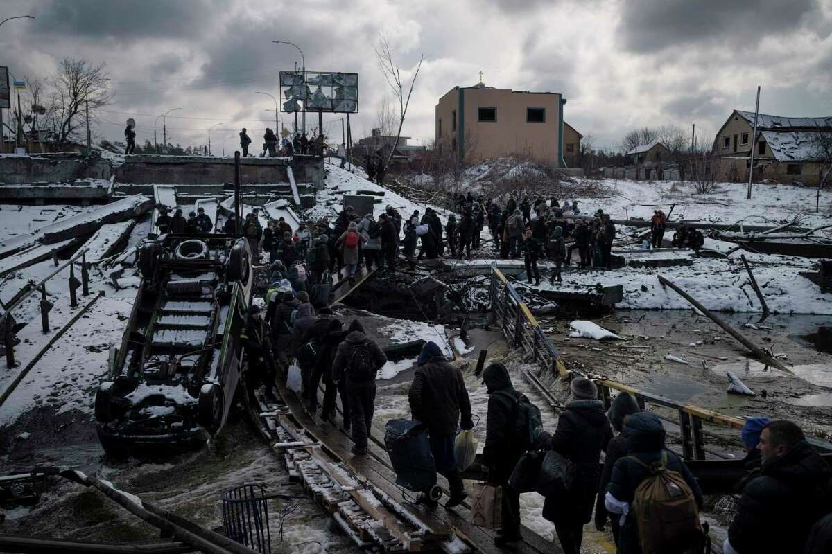 Ukrainians cross an improvised path under a destroyed bridge while fleeing Irpin, in the outskirts of Kyiv, Ukraine, Tuesday, March 8, 2022. Efforts to put in place cease-fires along humanitarian corridors have repeatedly failed amid Russian shelling.