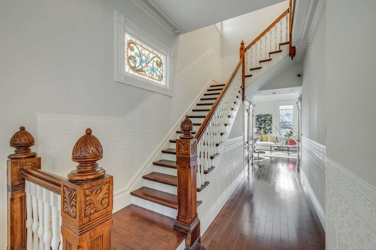 The carved wood of the staircase and gleaming hardwoods evoke the home's historic pedigree.