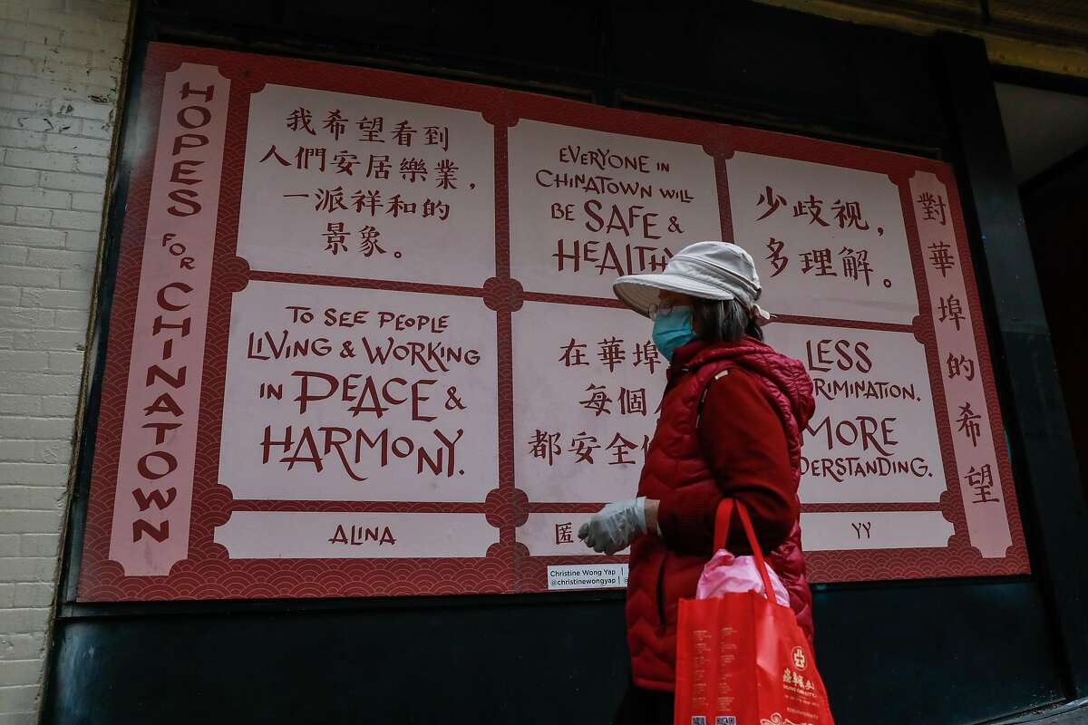 A woman walks past a mural promoting peace made by Christine Wong Yap (not pictured) on Clay Street in Chinatown on Wednesday, March 17, 2021 in San Francisco, California.San Francisco police officers are adding extra patrols in Asian neighborhoods in the wake of shootings in Atlanta that left several Asian women dead.