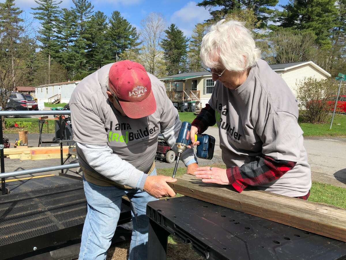 Two volunteers from Rebuilding Together Saratoga County work on a deck for a ramp to help a resident access their home.