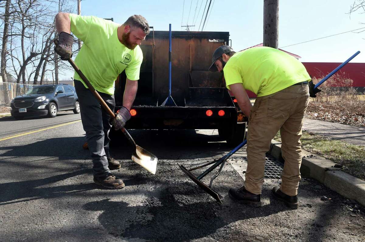 John Landino, left, and Ron Esposito of Hamden Public Works fill potholes on Putnam Avenue in Hamden Friday.