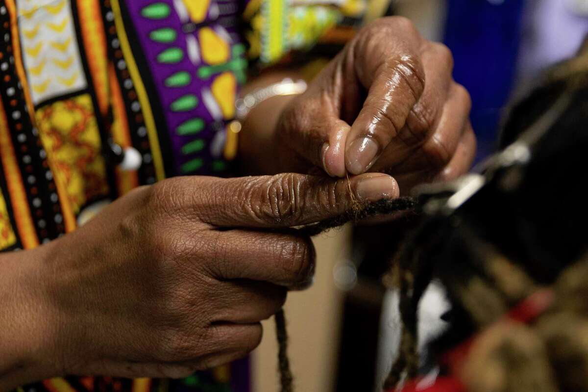 Davette Mabrie does a technique called palm rolling during a session with longtime client, LaShonda Hollins. Mabrie runs her own business, Davette’s Braids and Locs, and has been braiding hair for more than 40 years.