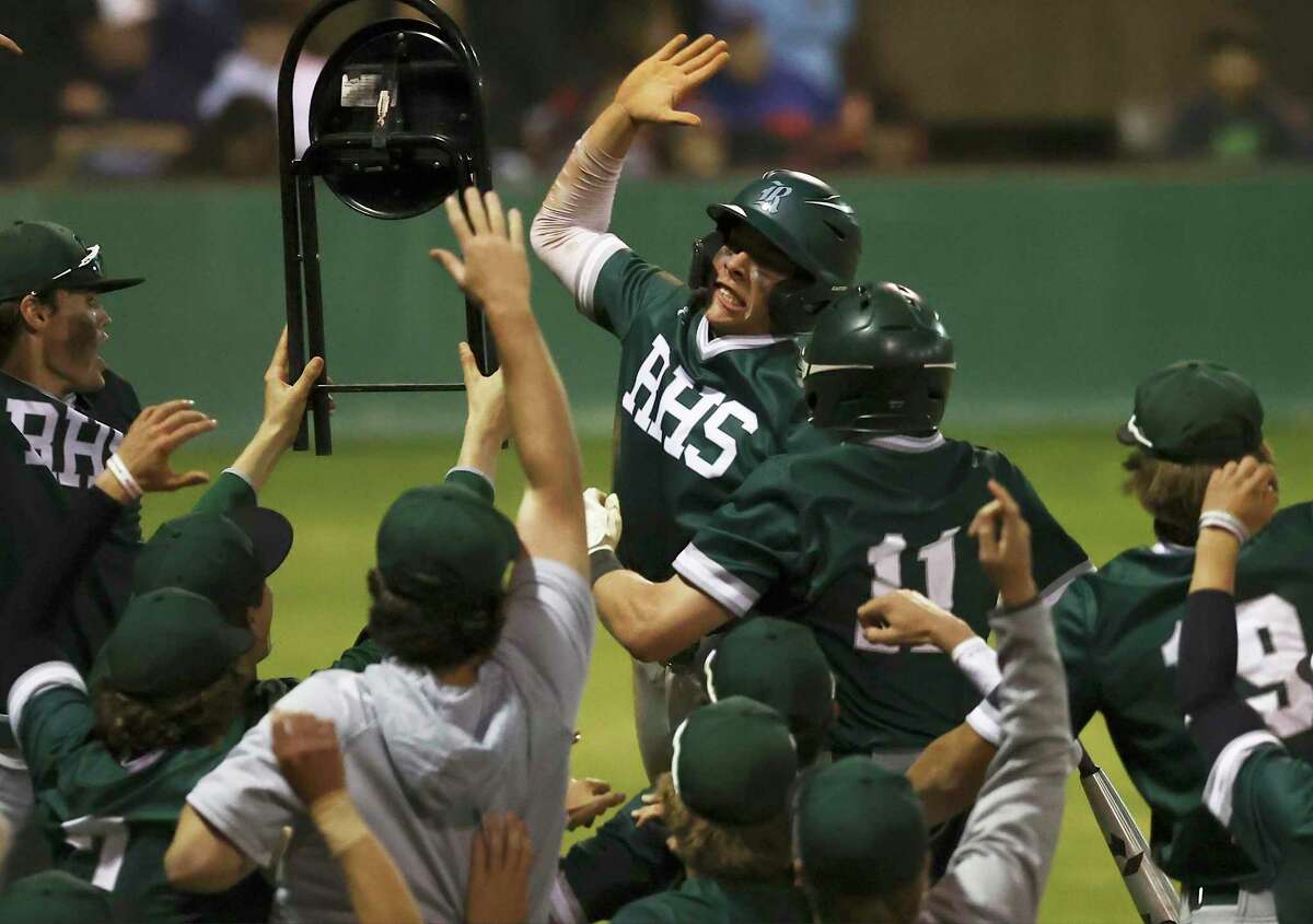 Reagan's Cole Tabor (center) leaps to celebrate after scoring one of eight runs by Reagan against Johnson during their baseball game at Blossom Athletic Center on Friday, Mar. 18, 2022.