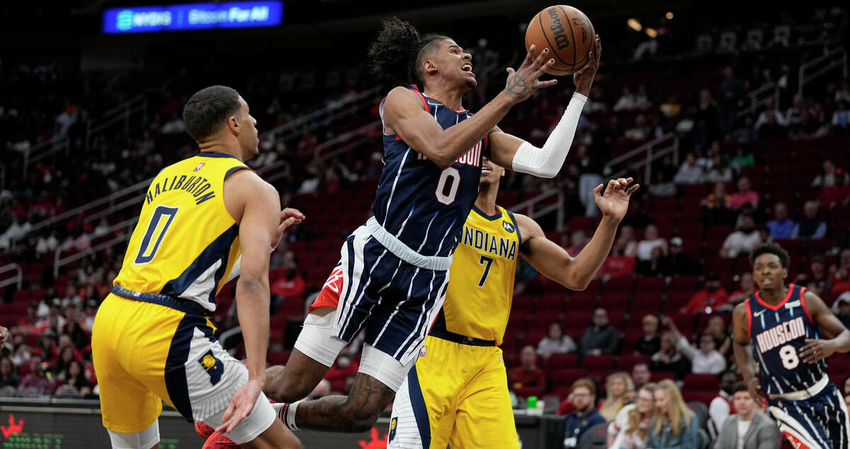 Houston Rockets' Jalen Green, center, goes up for a shot as Indiana Pacers' Tyrese Haliburton (0) and Malcolm Brogdon (7) defend during the second half of an NBA basketball game Friday, March 18, 2022, in Houston. The Pacers won 121-118. (AP Photo/David J. Phillip)