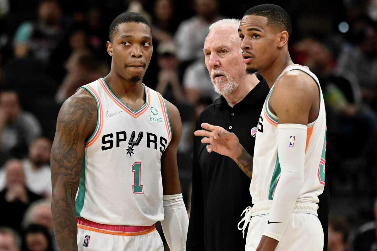 San Antonio Spurs head coach Gregg Popovich, center, talks to Spurs guards Lonnie Walker IV (1) and Dejounte Murray during the first half of an NBA basketball game against the New Orleans Pelicans on Friday, March 18, 2022, in San Antonio. New Orleans won 124-91. (AP Photo/Darren Abate)