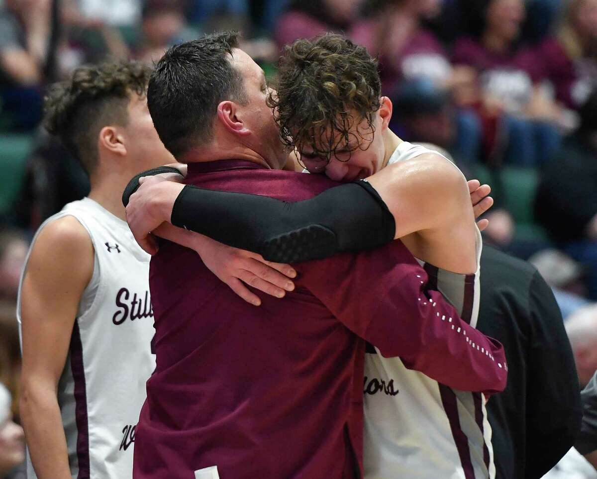 Stillwater's Jaxon Mueller, right, hugs head coach Bruce Lilac as he comes out of the Class C final against Newfield at the NYSPHSAA Boys Basketball Championships in Glens Falls, N.Y., Saturday, March 19, 2022. (Adrian Kraus / Special to the Times Union)