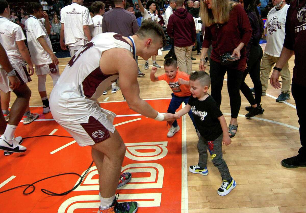 Bristol Central's Victor Rosa gets high fives from his cousins Lukey LoRusso, 4, and Nicholas LoRusso, 6, in center, as the team celebrates its win over Northwest Catholic in Div. II Boys Basketball state championship action at Mohegan Sun Arena in Uncasville, Conn., on Saturday March 19, 2022.