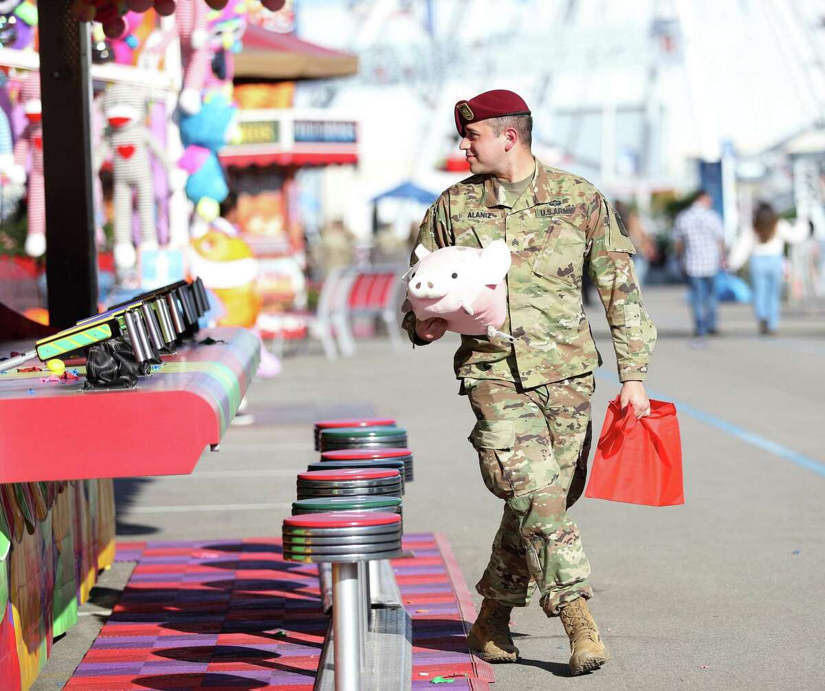 U.S. Army’s Leo Alaniz holds his stuffed pig, a prize won in a water balloon popping contest with a young girl in the Carnival area-after his victory, he gave her the stuffed pig during Armed Services Day at the Houston Livestock Show and Rodeo at NRG Park on Wednesday, March 2, 2022 in Houston.