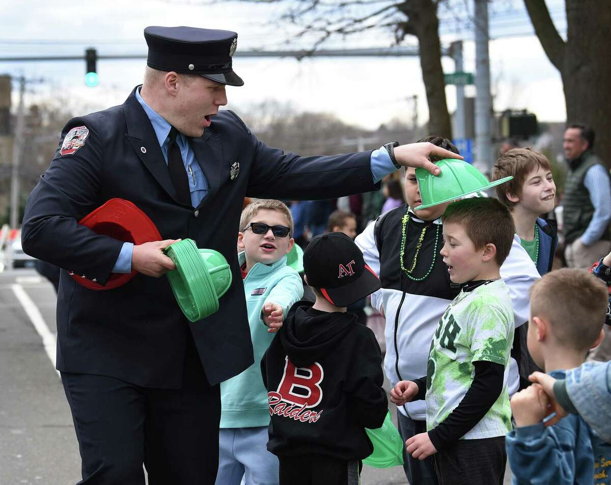 Greenwich firefighter Forrest Edelman leaves the parade formation to hand out plastic helmets to kids on the parade route. Greenwich's annual St. Patrick's Day Parade is held Sunday, March 20, 2022, after a two year break due to Covid-19 restrictions.