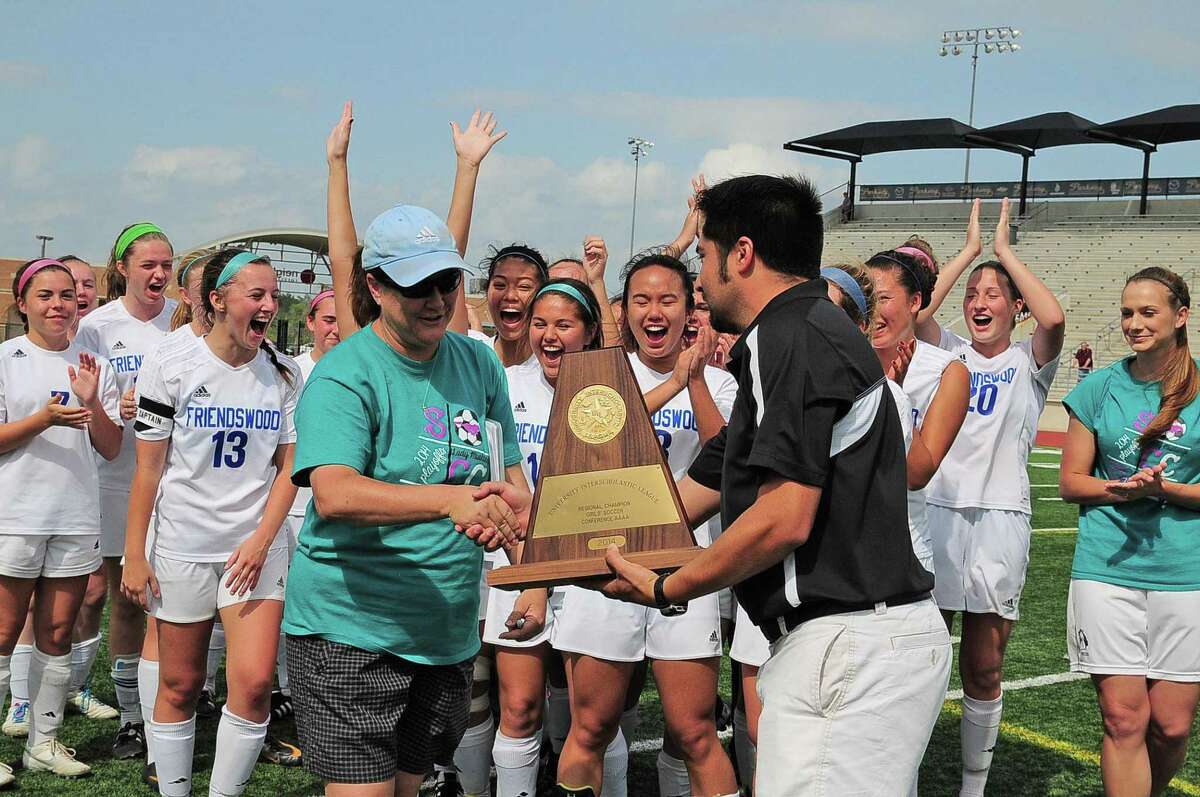 Friendswood head coach Laura Peter accepts the trophy after the Lady Mustangs defeated College Station 2-0 in theRegion 3-4A Championship in 2014 in Humble.