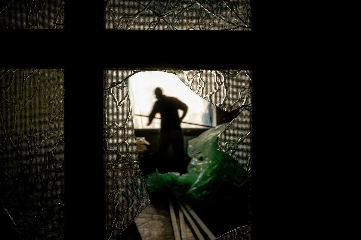 Slava Chikov covers the shattered window of his living room with a plastic sheet Monday, March 21, 2022 in a building damaged by a bombing that occurred the previous day in Kyiv, Ukraine.