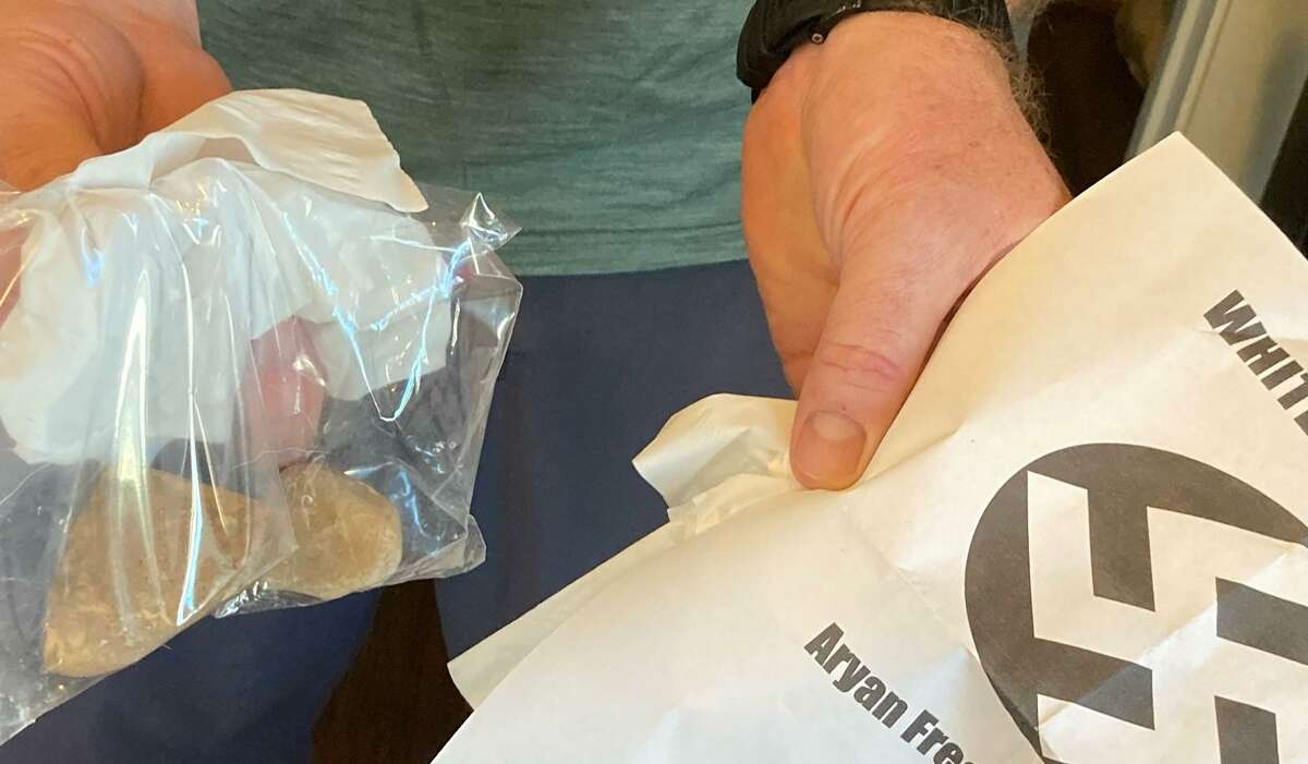 A man holds a racist flyer left on his front lawn in a plastic bag filled with rocks March 20, 2022, in the Heights.