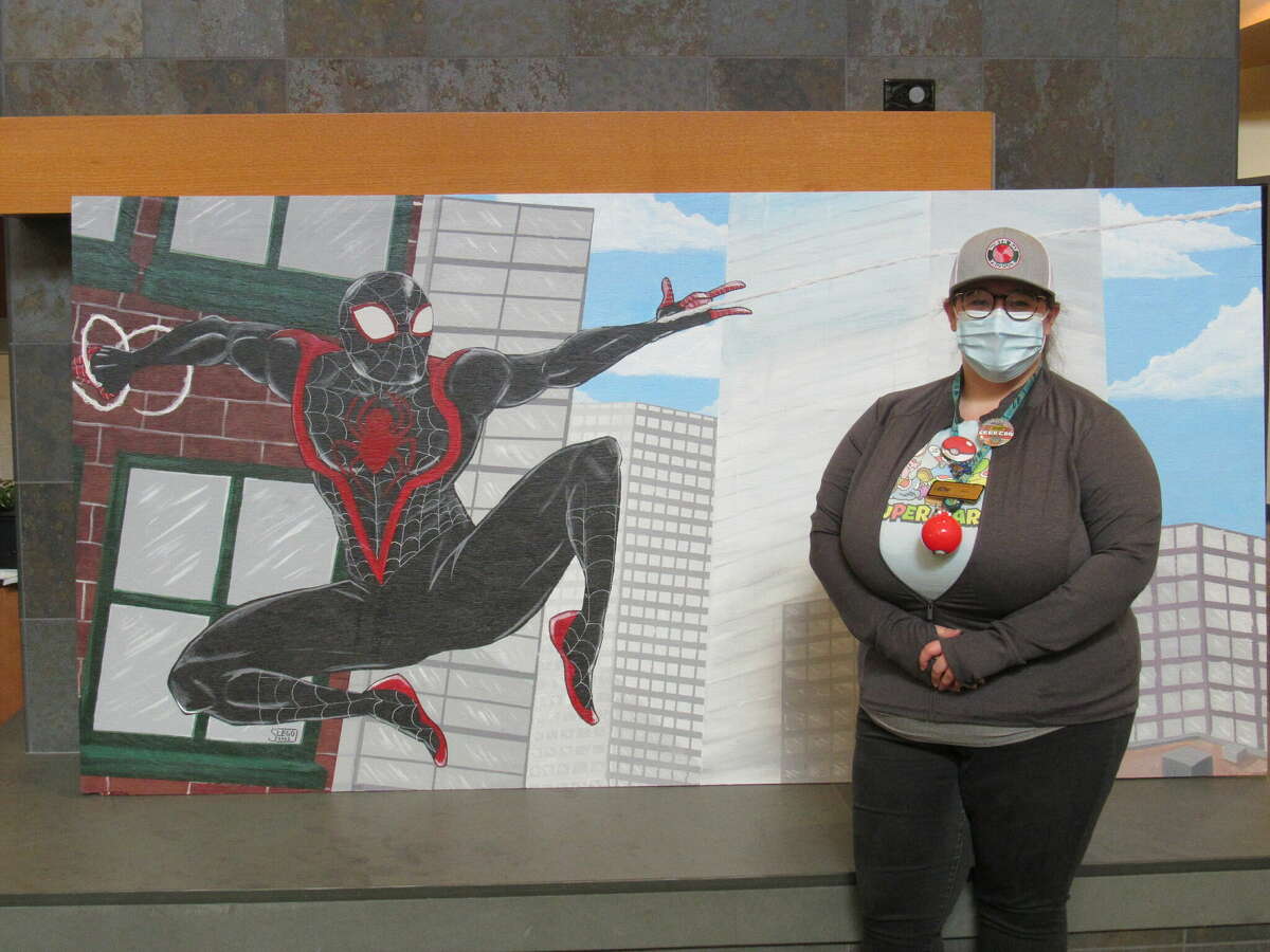 Glen Carbon Library Youth Services Librarian Samantha Lego stands with the mural of Spider-Man that she painted for Saturday's Geek Con. 