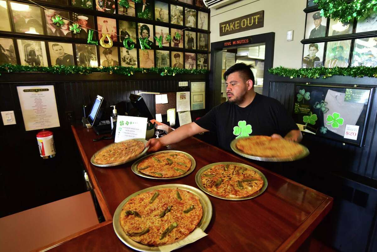 Colony Grill employee Hector De la Rosa brings out fresh pies at their Myrtle Avenue location in Stamford, Conn., on Friday March 18, 2022. Colony Grill has been a mecca for pizza since 1935 and serves locals at its original location. Colony Grill has expanded over the years, with restaurants now in Florida.