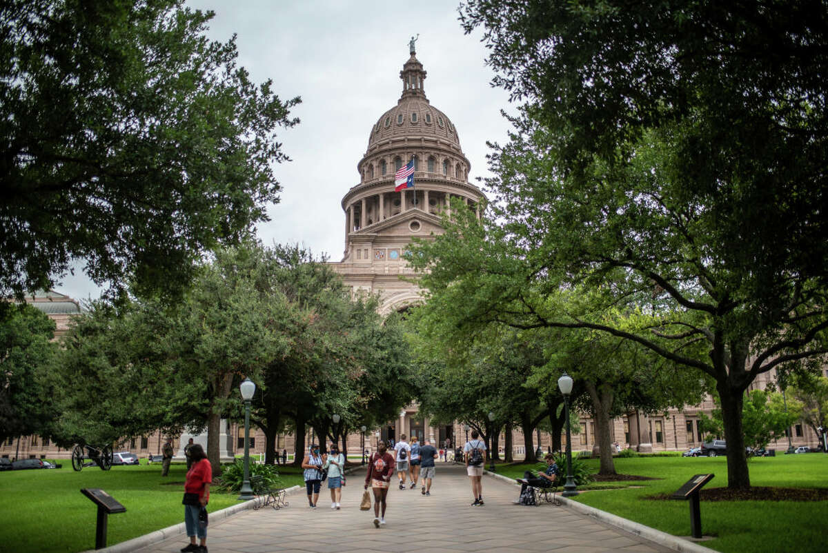 Visitors walk around outside the Texas State Capitol building on July 12, 2021 in Austin, Texas. (Photo by Sergio Flores/Getty Images)