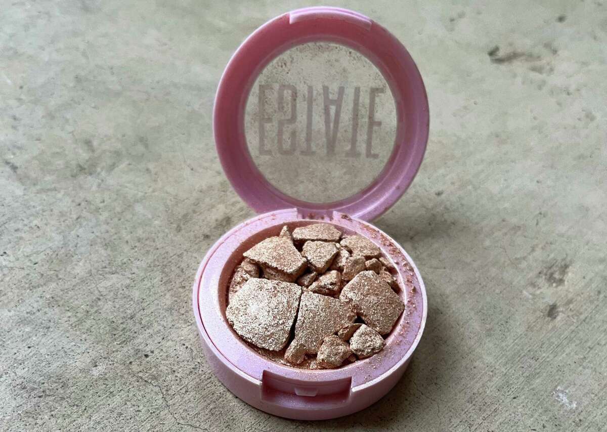 This highlighter makeup - barely used and broken - is among the makeup waste found in a trash bin.