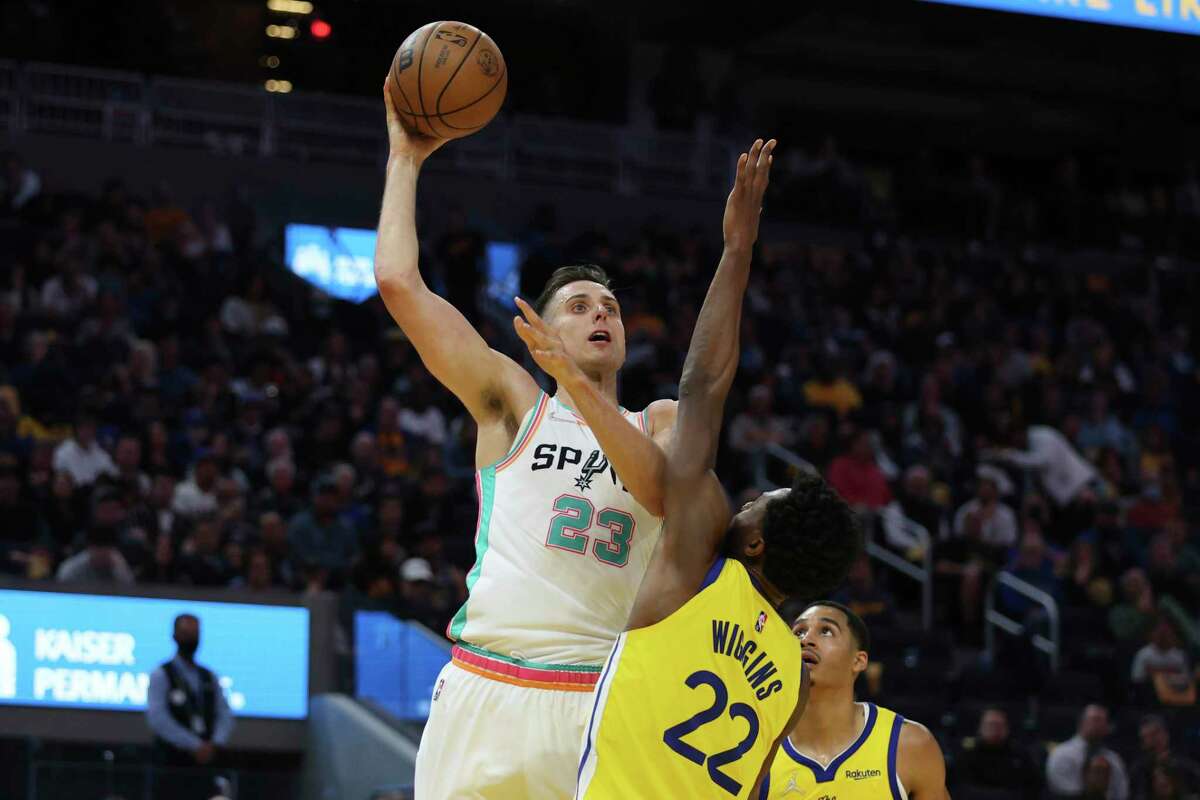 San Antonio Spurs forward Zach Collins (23) shoots against Golden State Warriors forward Andrew Wiggins (22) during the first half of an NBA basketball game in San Francisco, Sunday, March 20, 2022.