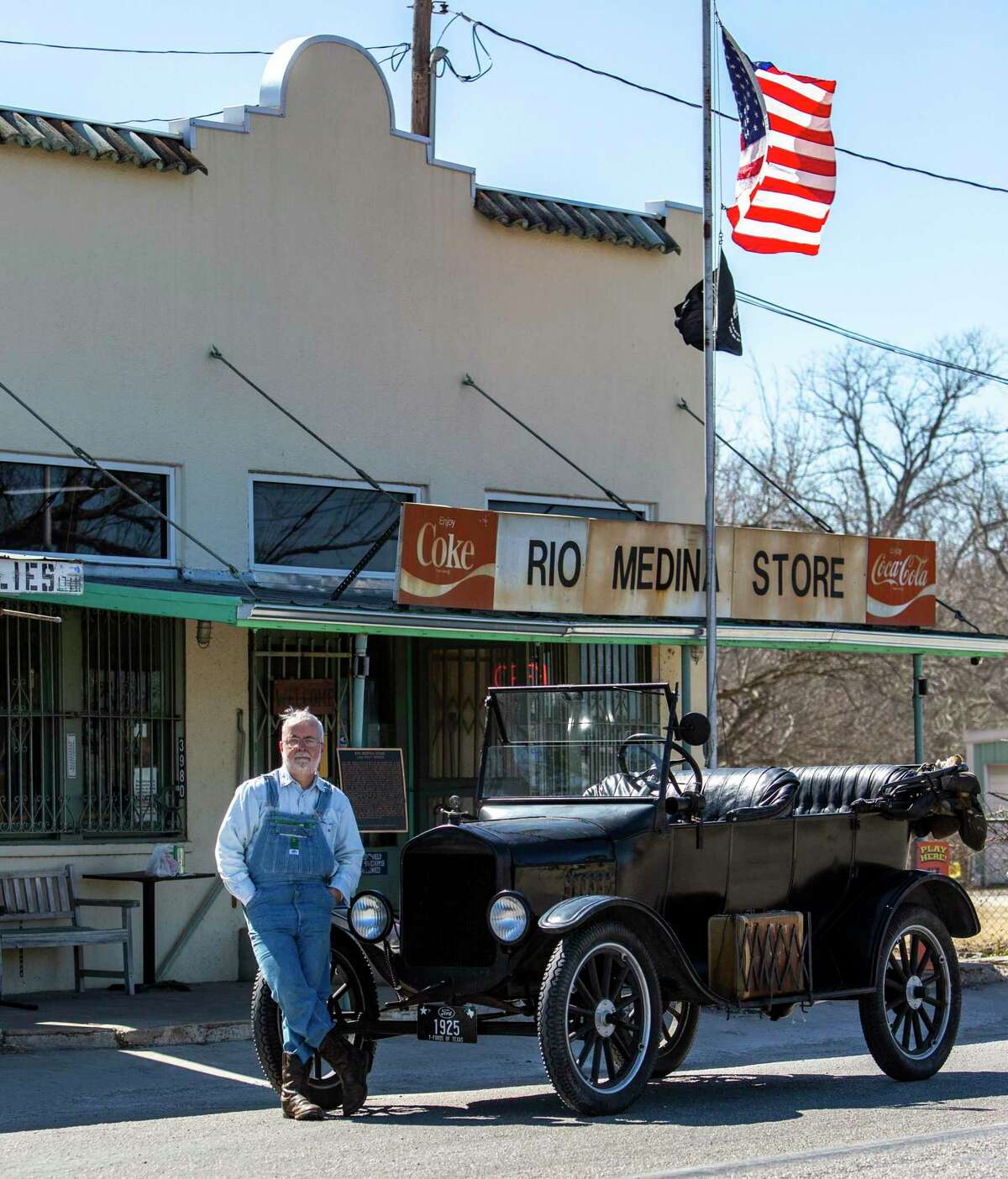 Hugh Hemphill, president of the San Antonio Ford Model T Club, poses with his car in front of the Rio Medina Store.