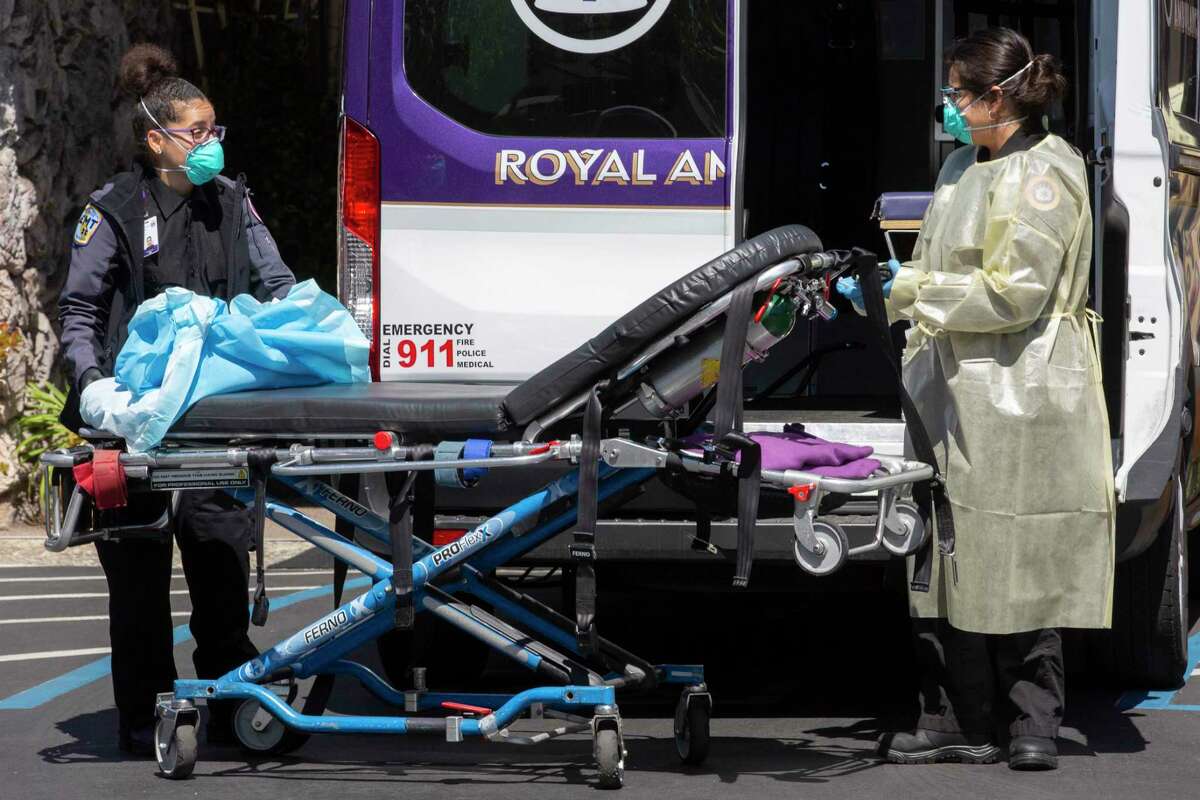 Two EMT?•s take off their protective gowns and disinfect their ambulance after transporting a person to Excell Health Care Center on Friday, April 24, 2020, in Oakland, Calif. Three people have died from COVID-19 at the nursing home, located at 3025 High Street in East Oakland. At the 99-bed facility, 36 residents and 17 staff members have tested positive for the coronavirus.