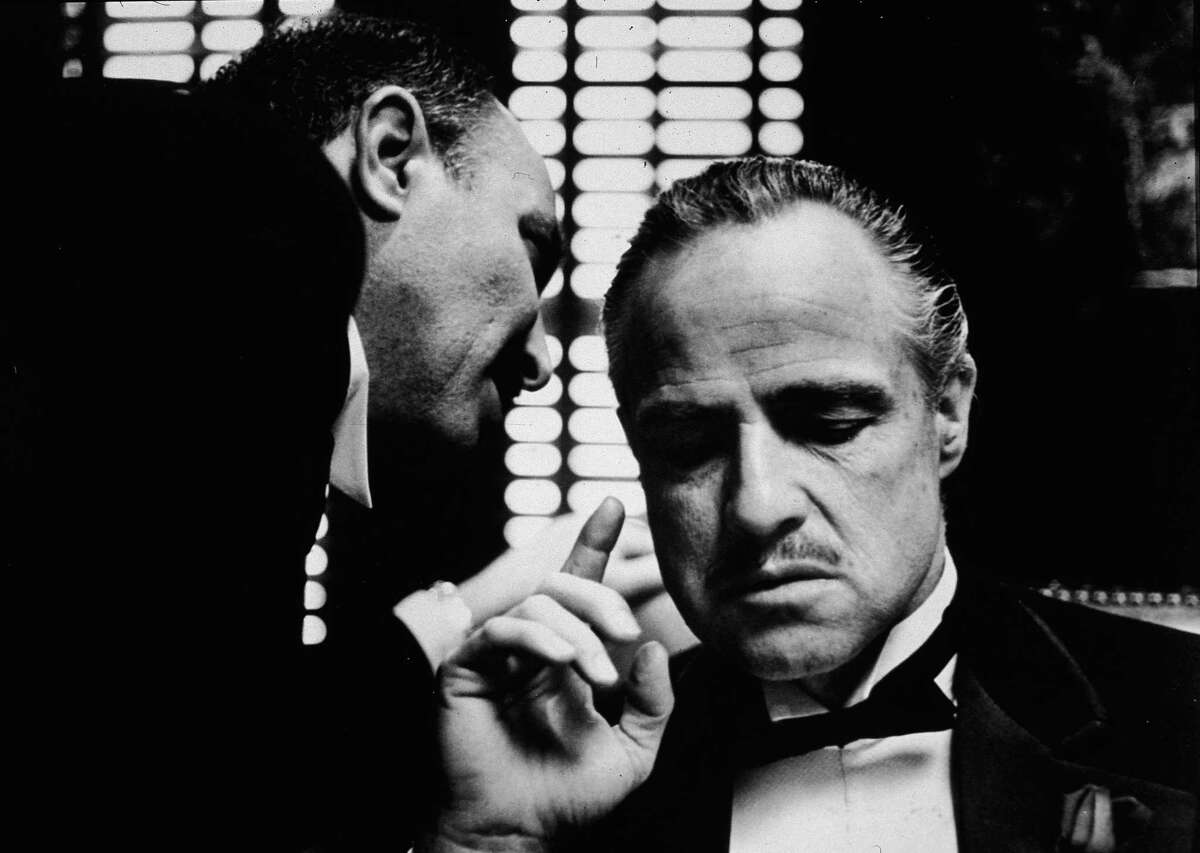 American actor Marlon Brando listens as an unidentified actor speaks close to one ear in a still from the film, “The Godfather,” directed by Francis Coppola, which was released on March 24, 1972.