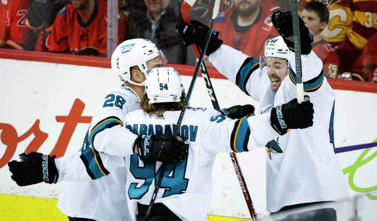 San Jose Sharks' Alexander Barabanov, center, celebrates his goal against the Calgary Flames with Timo Meier, left, and Tomas Hertl during the third period of an NHL hockey game Tuesday, March 22, 2022, in Calgary, Alberta. (Jeff McIntosh/The Canadian Press via AP)