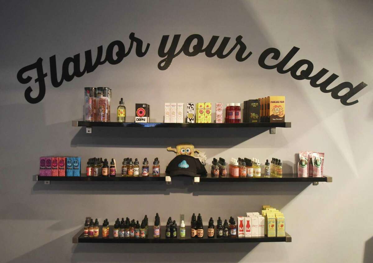 FILE PHOTO: Dozens of flavors of e-liquids are displayed at CLOUDS Vapors & Lounge in Greenwich in 2016. Connecticut’s proposed bill to prohibit the sale of flavored vapes continues to face resistance.