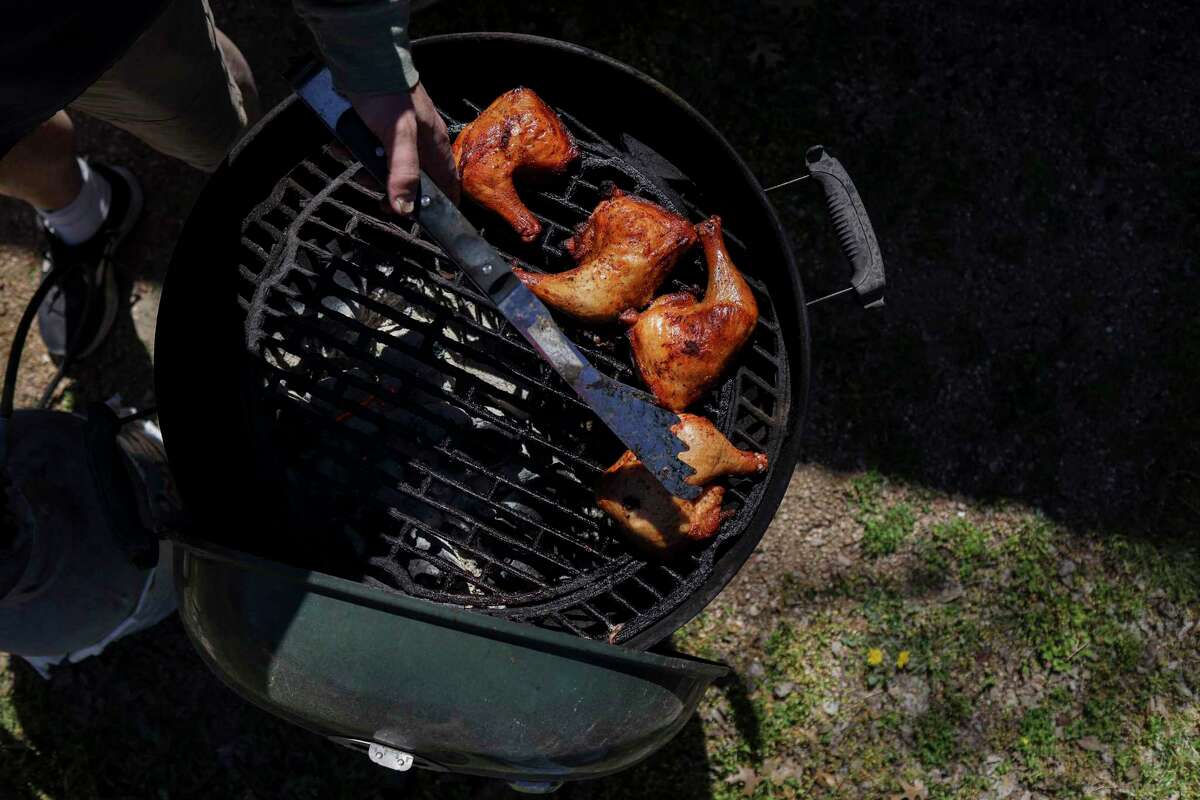 San Antonio Express-News Food Writer Chuck Blunt pulls chicken quarters with crispy skin off the grill.