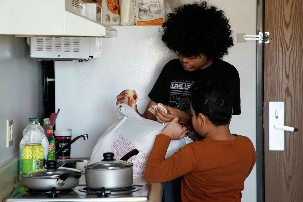 Daniel, center, breaks in half a pastry to share with his little brother, Ezequiel, while living in a long-stay hotel on Wednesday, March 16, 2022, in Conroe. Their mom was recently evicted after being denied rent relief because of her immigration status.