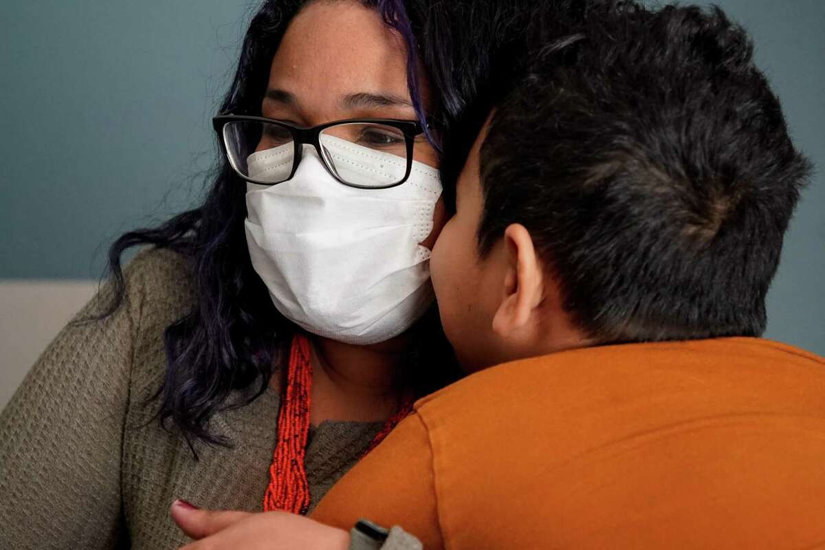 Ezequiel kisses his mom, Gaby Velasquez, inside their room in a long-stay hotel on Wednesday, March 16, 2022, in Conroe. Velasquez was recently evicted after being denied rent relief because of her immigration status.
