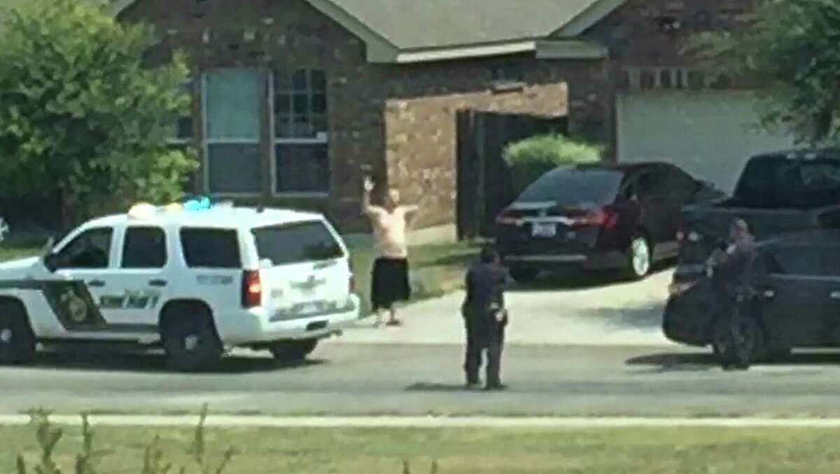 A video frame grab shows Gilbert Flores with his hands in the air and two Bexar County deputies, guns drawn, attempting to arrest Flores. Less than a second later, Flores would be shot and killed by the deputies. The video was shot by a neighbor and was released by the sheriff's department on Friday, 12/11/15.