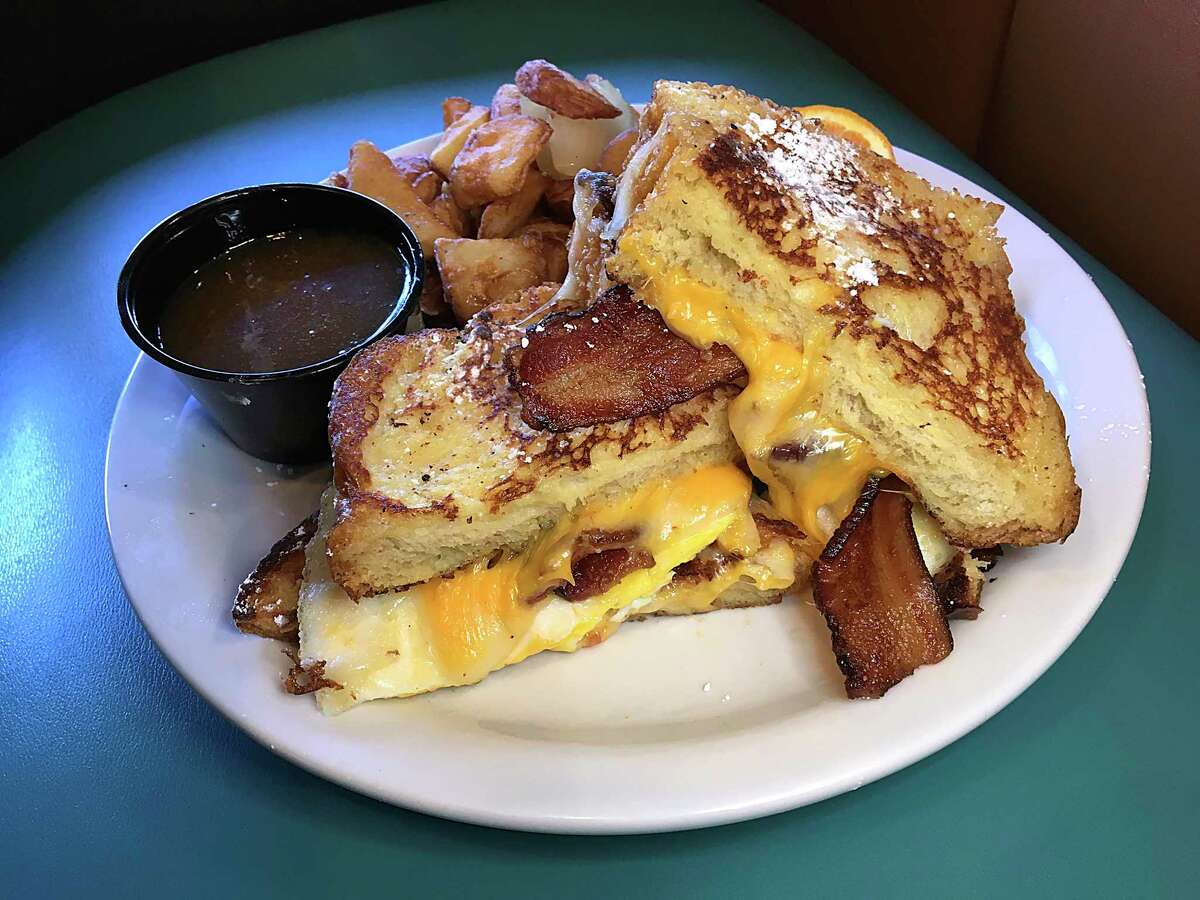 A French toast grilled cheese sandwich incorporates house-baked challah bread with cheese, bacon, warm maple butter and homefries at Max & Louie's New York Diner.