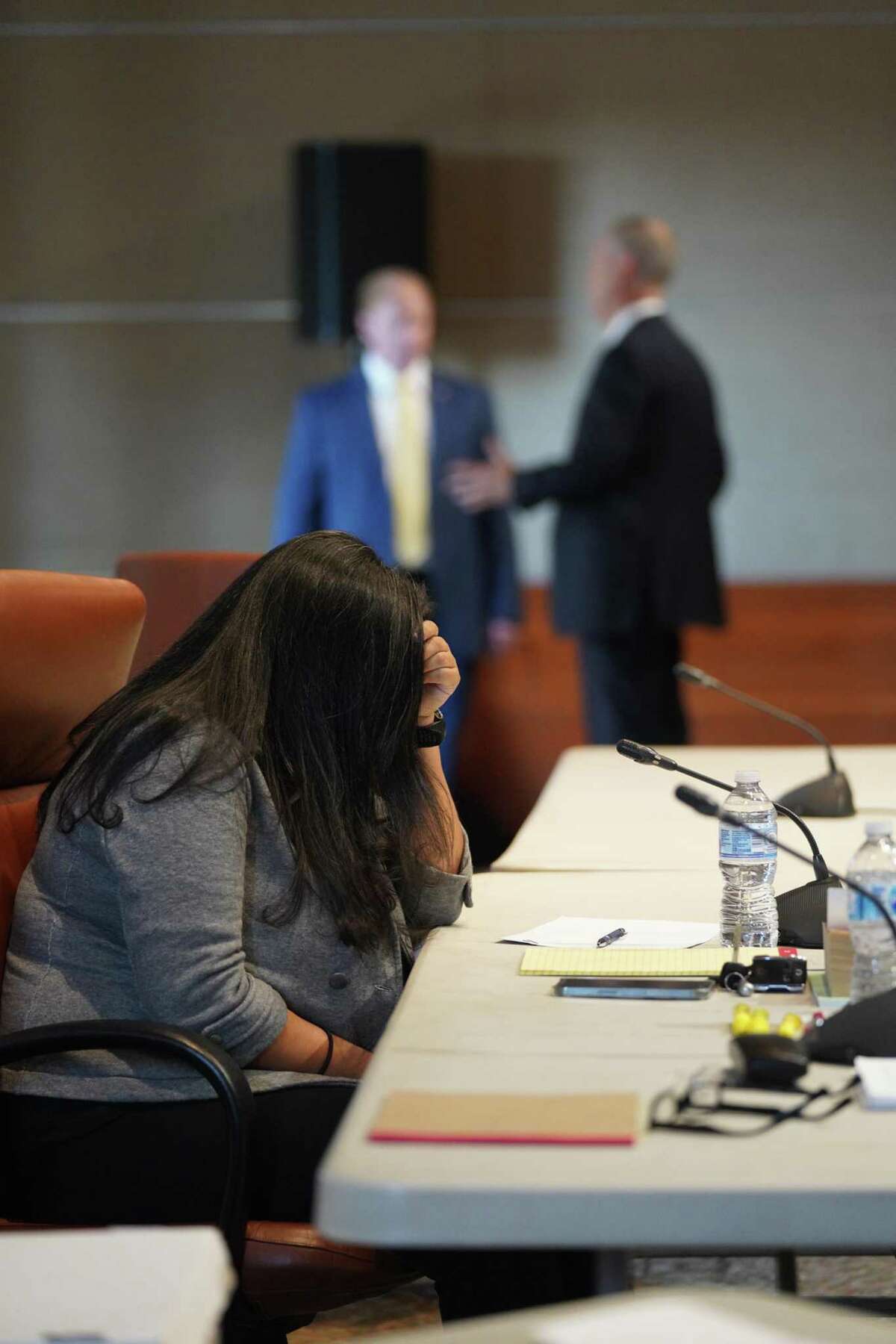 Former San Antonio police officer Elizabeth Montoya keeps her head down as her attorney, Robert Leonard, speaks with Assistant City Attorney Michael Urbis Tuesday morning during an arbitration hearing on her appeal of an indefinite suspension from the San Antonio Police Department.