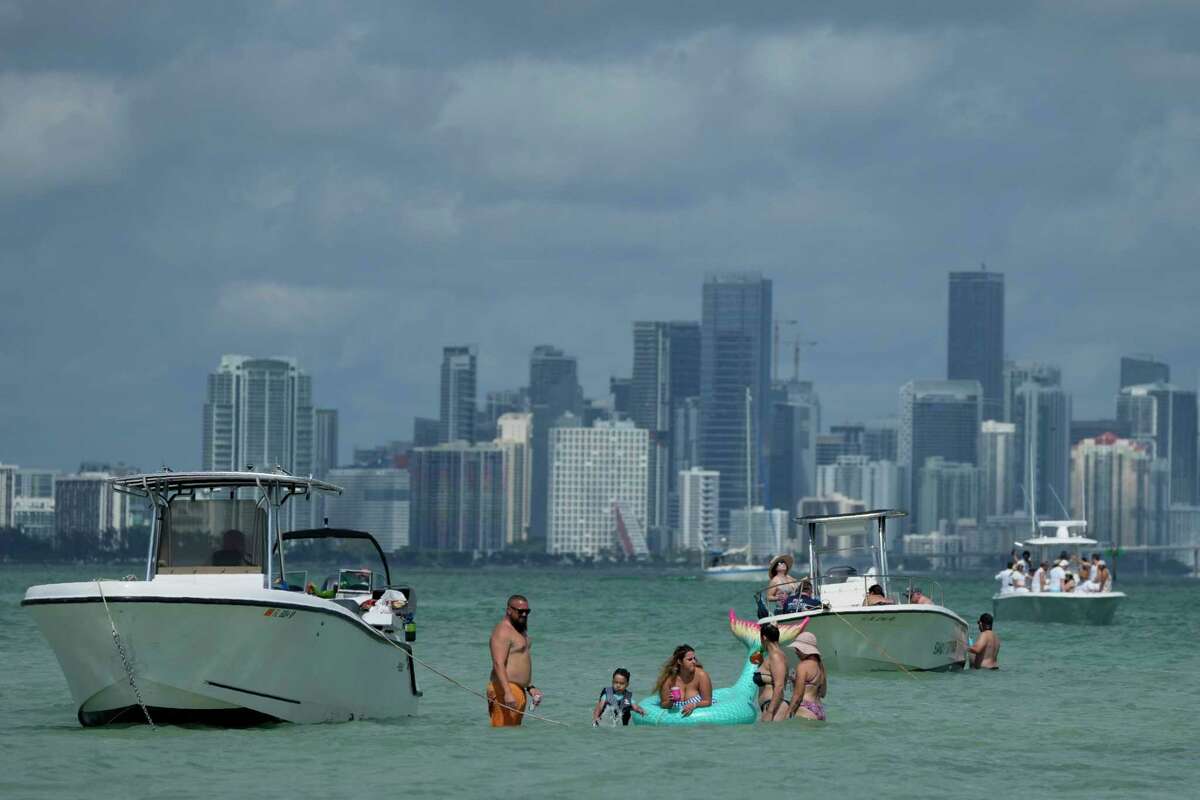 Boaters cool off on a sandbar with the Miami skyline seen in the background, Sunday, Feb. 27, 2022, in Key Biscayne, Fla.