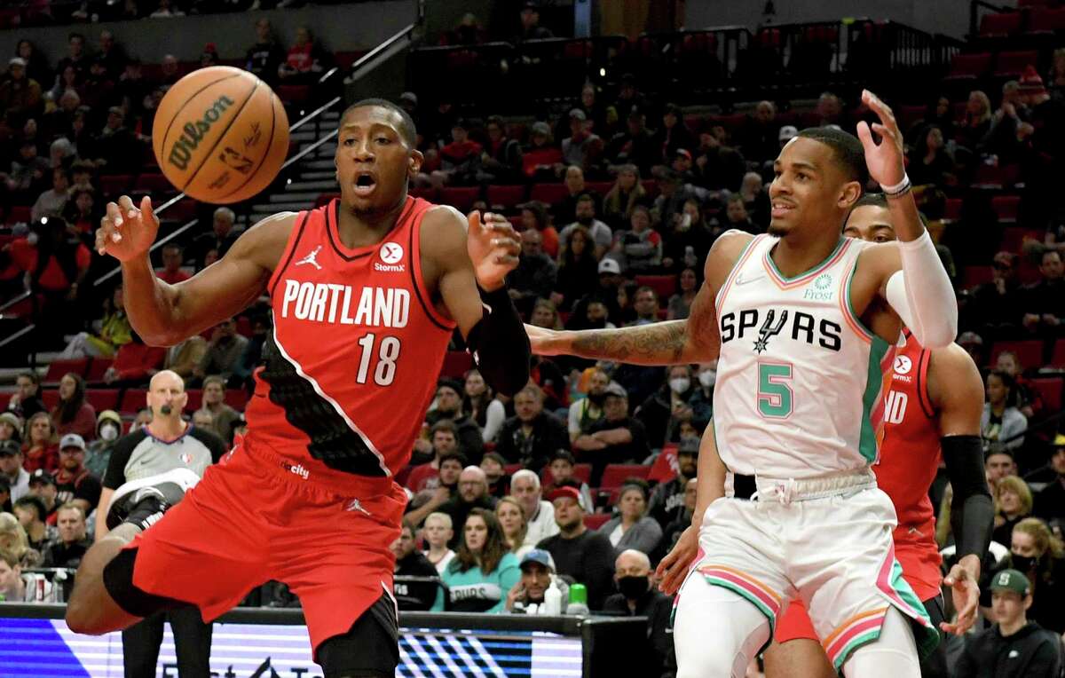 Portland Trail Blazers guard Kris Dunn, left, and San Antonio Spurs guard Dejounte Murray go after a rebound during the first half of an NBA basketball game in Portland, Ore., Wednesday, March 23, 2022. (AP Photo/Steve Dykes)
