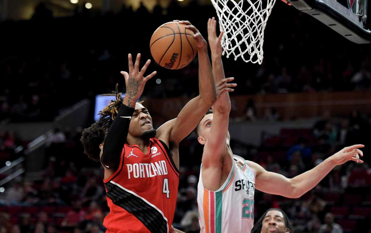 Portland Trail Blazers forward Greg Brown III, left, and San Antonio Spurs forward Zach Collins go after a rebound during the first half of an NBA basketball game in Portland, Ore., Wednesday, March 23, 2022. (AP Photo/Steve Dykes)