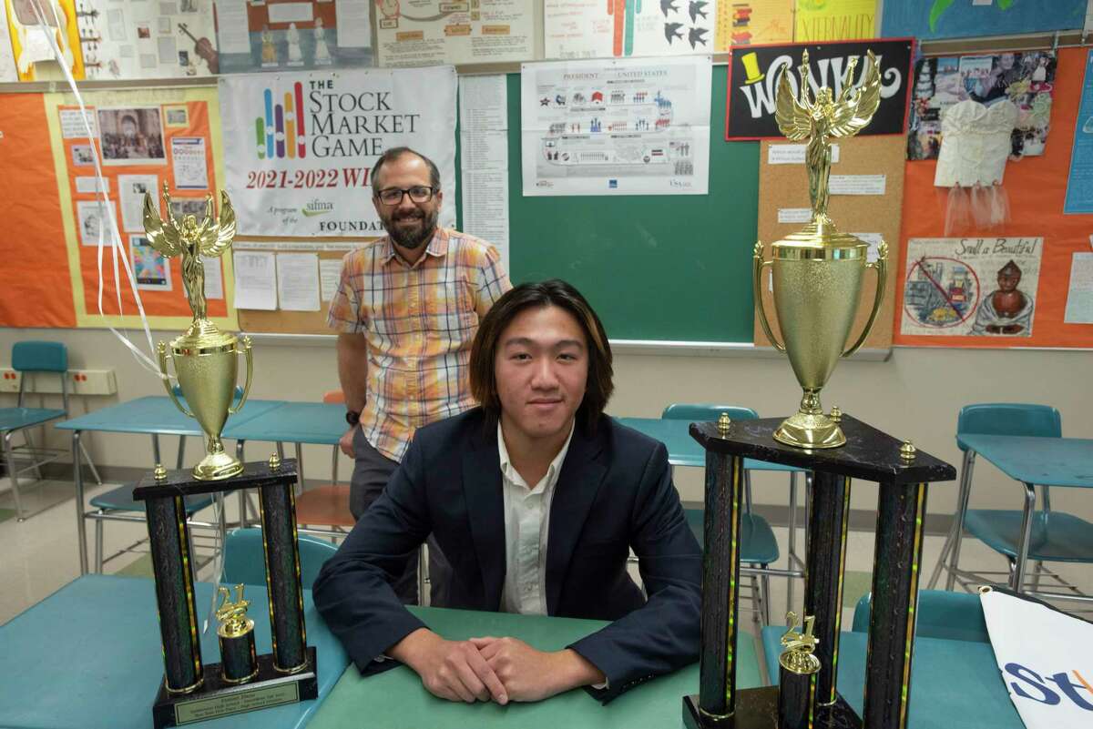 Bethlehem High School senior, Daniel Zhou, foreground, poses with his economics teacher Jason Majewski on Thursday, March 24, 2022, in Bethlehem, N.Y. Zhou on Thursday was awarded two trophies by the SIFMA Foundation for his first place in the state and first place in the nation in the organization's InvestWrite competition. Zhou received $100 for placing first in New York State, and $750 for placing first in the nation in the competition. There is also $100 awarded to go towards some type of celebration Zhou can hold with his classmates at school. (Paul Buckowski/Times Union)
