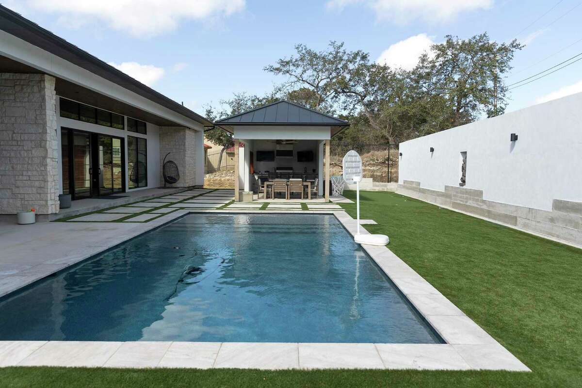 The backyard has a pool, a covered bar, a shaded outdoor seating area and a putting green.