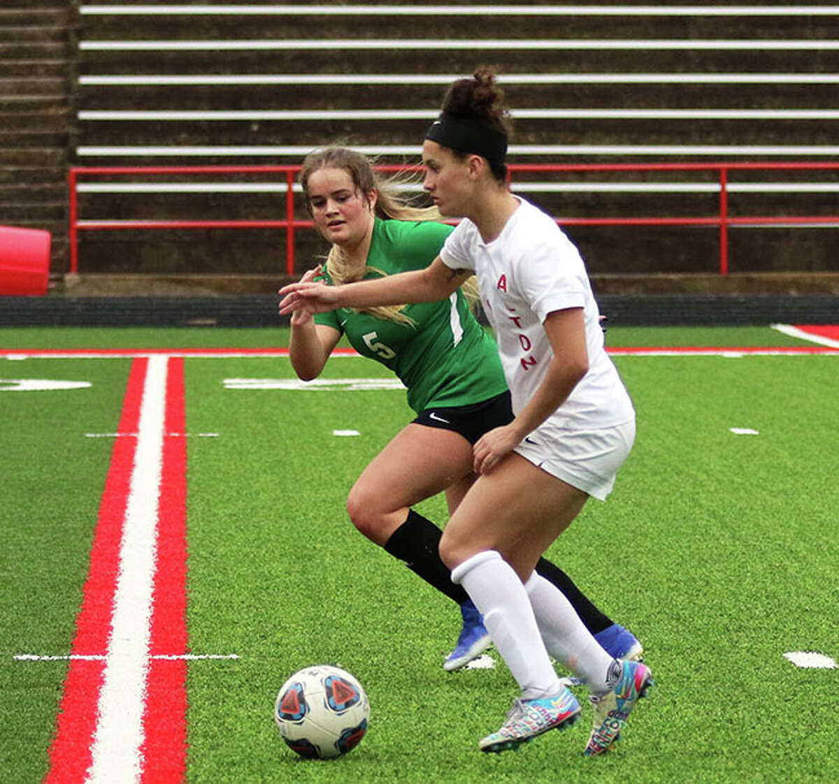 Alton's Emily Baker (left) pushes the ball toward the goal while Southwestern's Jillian Smith defends in a match Tuesday at Public School Stadium in Alton. Smith had a hat trick in that 8-0 win and came back Thursday with another hat trick in the Redbirds' 7-1 win over Belleville West in Alton.