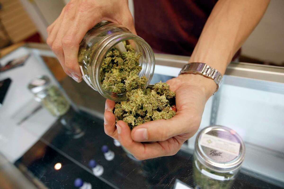 A budtender pours marijuana from a jar at Perennial Holistic Wellness Center medical marijuana dispensary in Los Angeles, Calif.